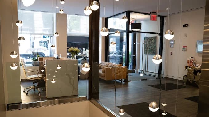 Glass-walled lobby with brass pendant lighting at the entrance to the studio